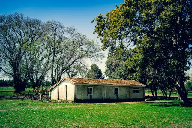 Edificio rural de un piso en un potrero con árboles