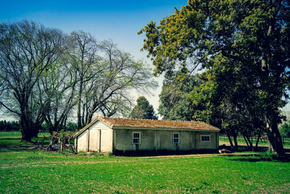 Edificio rural de un piso en un potrero con árboles
