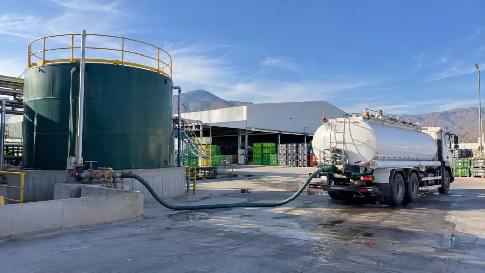 Camión cisterna cargando riles desde un estanque de acumulación en una planta de packing con bins de fruta
