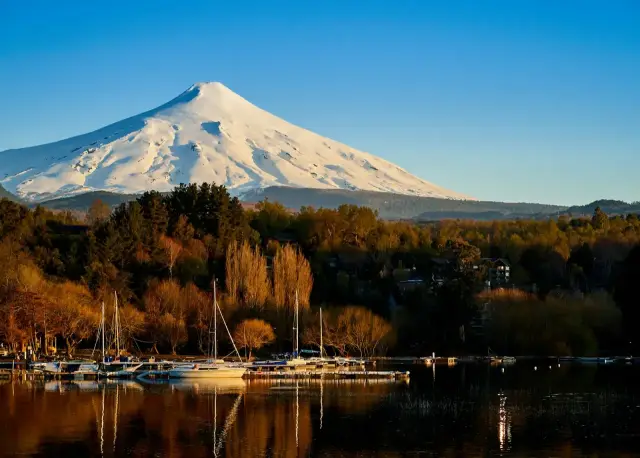 Volcán Villarrica nevado sobre el lago, con veleros